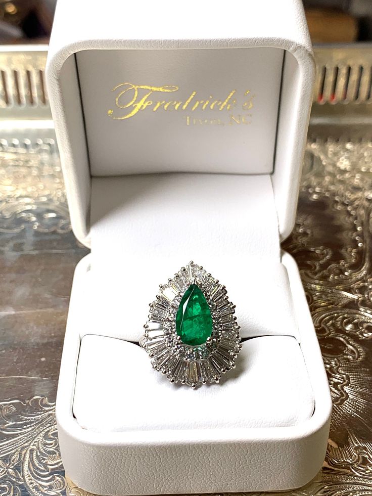 Elegant pear shape Kelly-green Colombian emerald, approximately 2.75 ct. set with 14 round diamonds total weight 70 points, brilliant cut SI-1, H color. Along with 32 tapered baguettes, very fine quality VS, approximately 2 carat total weight.  Total weight of ring 7g Please inquire about this item. Emerald & Diamond Ring MATERIAL 14K Gold, white Diamonds SIZE 5 Luxury Pear-shaped Emerald Ring For Formal Occasions, Luxury Pear-shaped Emerald Ring With Prong Setting, Formal Pear-shaped Emerald Ring In White Gold, Gia Certified Pear-shaped Diamond Emerald Ring, Gia Certified Green Pear-shaped Diamond Ring, Elegant Emerald Diamond Pear-shaped Ring, Formal Pear-shaped Emerald Ring With Halo Setting, Elegant Pear-shaped Emerald Diamond Ring, Formal Pear-shaped Brilliant Cut Emerald Ring