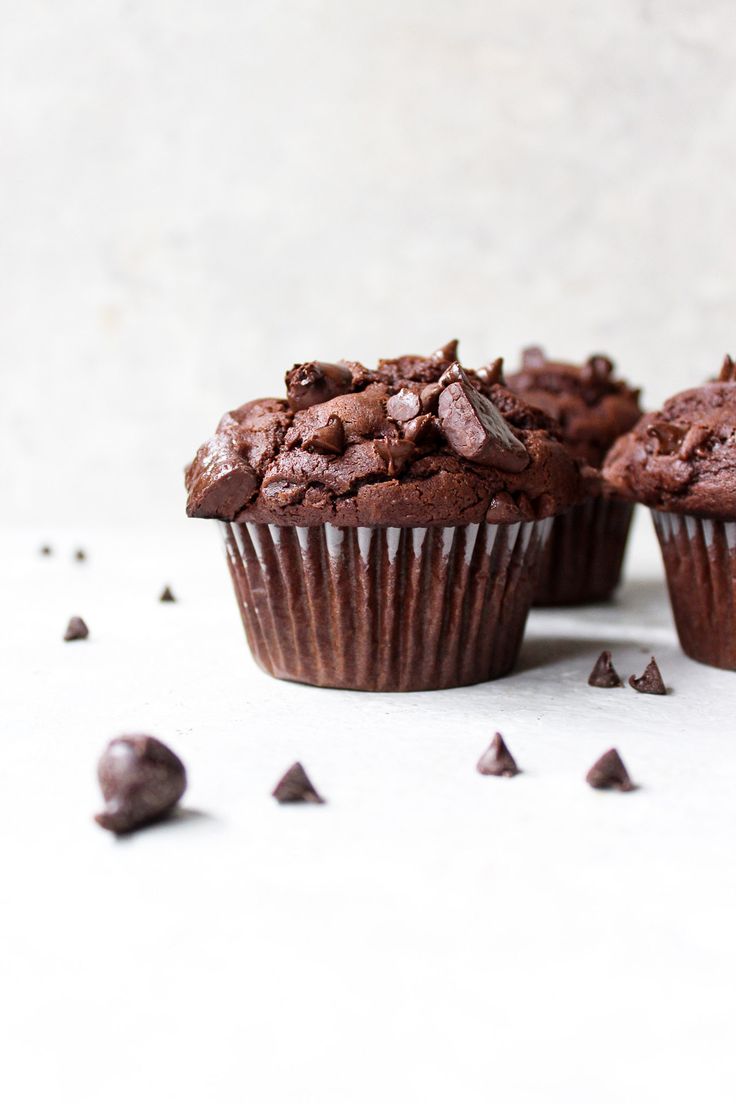 three chocolate muffins sitting next to each other on top of a white table