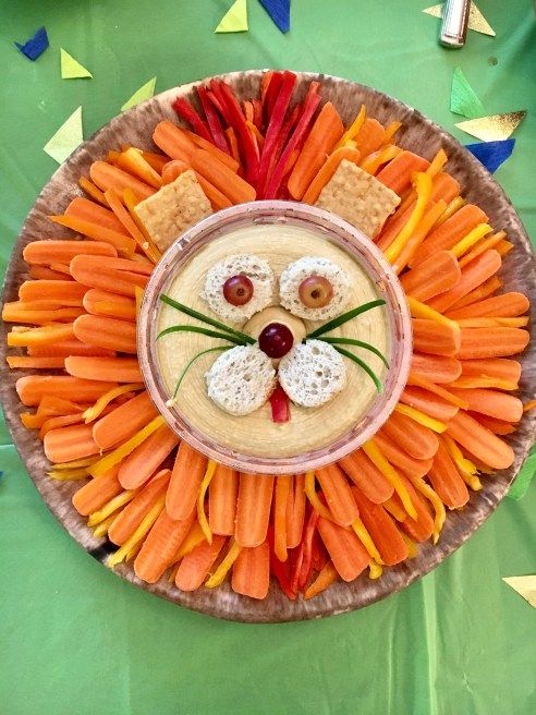 a plate with carrots and crackers in the shape of a lion's face