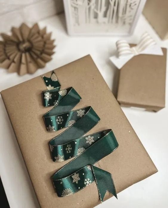 three christmas trees made out of brown paper and green ribbon on top of a white table