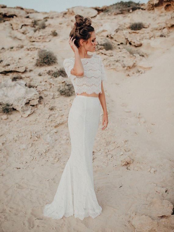 a woman standing on top of a sandy beach next to the ocean wearing a white dress