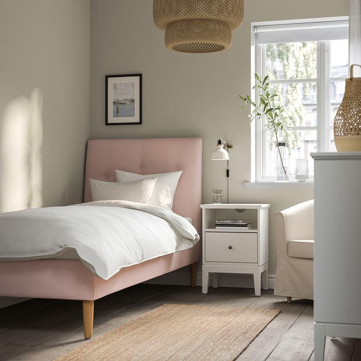 a bedroom with a pink bed and white sheets on the bed, next to a window