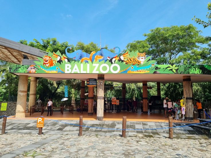 the entrance to an animal zoo with people standing around it and trees in the background