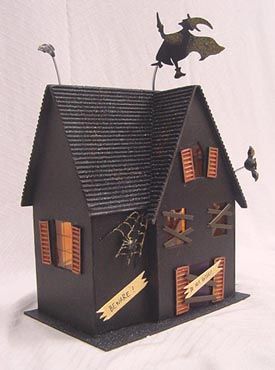 a black house with halloween decorations on the roof and bats flying over it's windows