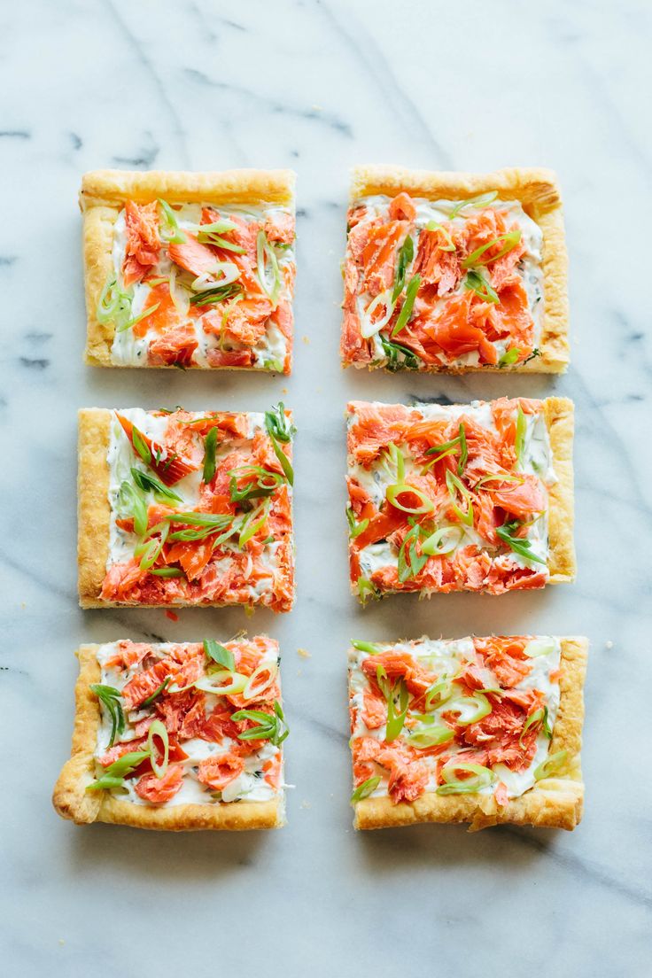 four square crackers with various toppings arranged on a marble countertop, top view