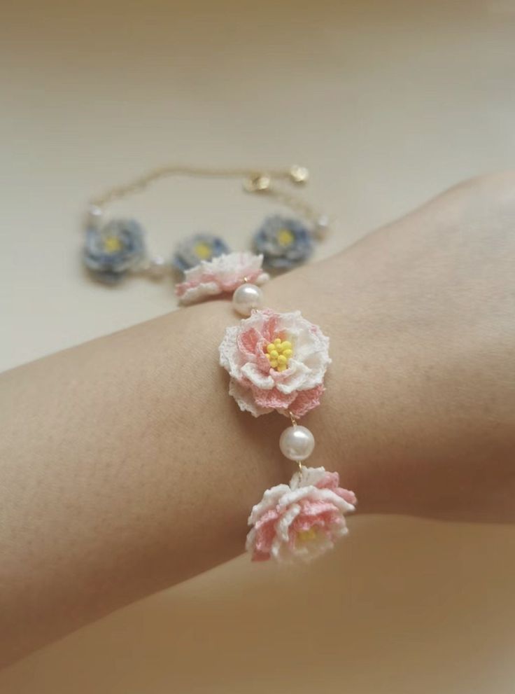 a woman's arm with flowers and pearls attached to the bracelets on it