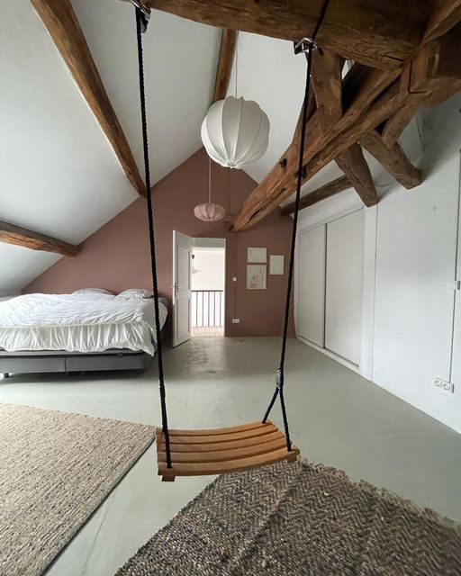 a bedroom with a bed, hanging chair and other items in the room on the floor