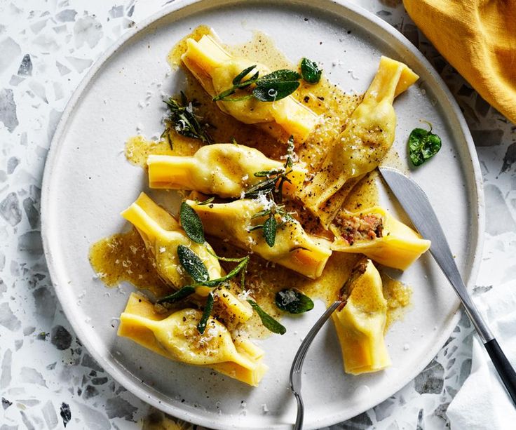 a white plate topped with ravioli and parmesan cheese next to a yellow napkin