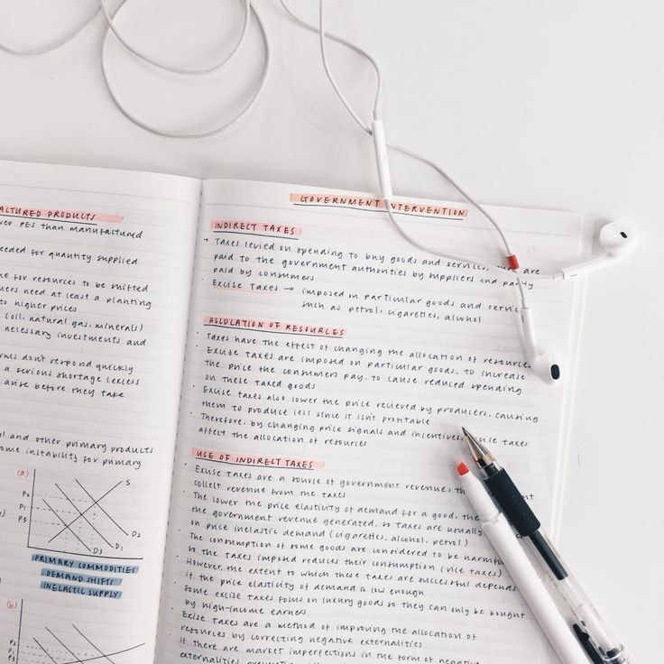 an open book with headphones on it next to a pen and earbuds