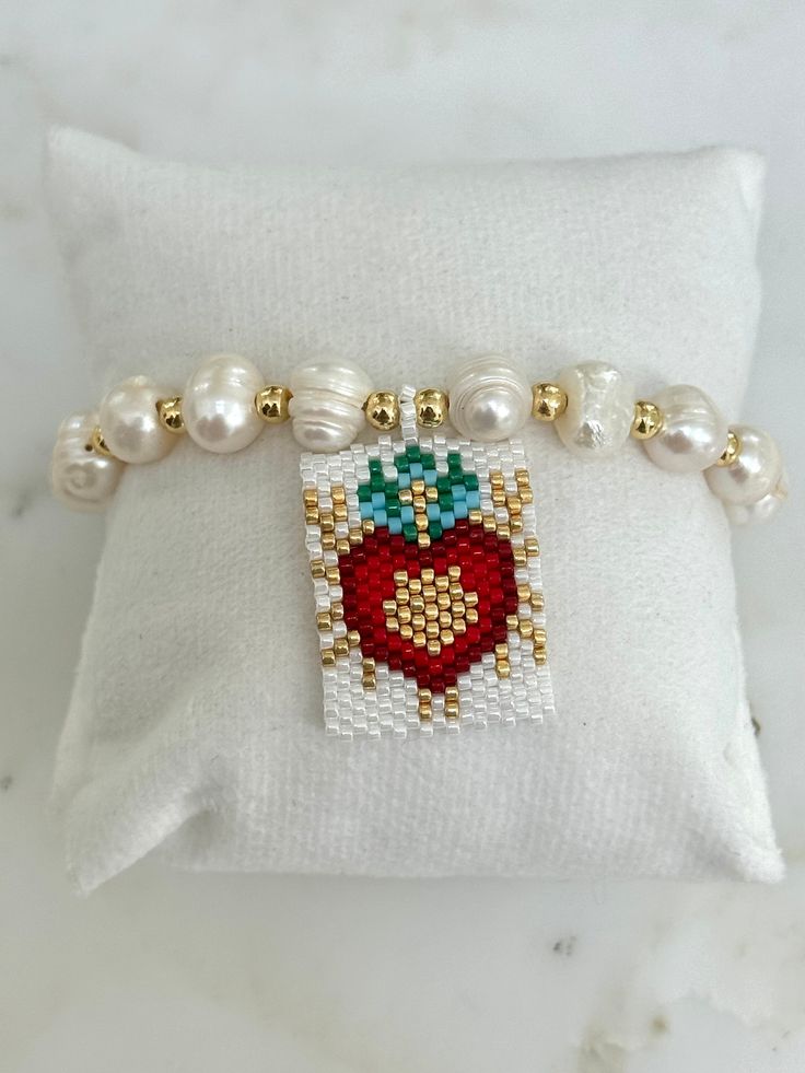 This Woven Heart Miyuki Beads Adjustable Bracelet is made with the following: Size & Material: - Features 8mm pearls and 4mm gold beads all strung on a cord  - The centerpiece showcases the Sacred Heart of Jesus, intricately crafted from small glass beads in white, red, gold, and turquoise. - The miyuki beads centerpiece measure 1'' x 1.25'' - The bracelet measures approximately 11'' long  - Adjustable cord for perfect fit The ideal gift for those devoted to the Sacred Heart of Jesus, perfect fo Heart-shaped Beads For Valentine's Day Gift, Heart Beads For Valentine's Day Gift, Heart-shaped 8mm Bead Jewelry Gift, White Pearl Bracelets With Heart Beads, Gold Heart Bracelet With Round Handmade Beads, Dainty Handmade Heart-shaped Beaded Bracelets, Pearl Beaded Bracelets With Heart Beads, Heart Bracelet With Round Beads As Gift, Heart Bracelet With Tiny Beads For Gift