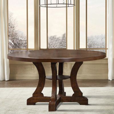 a round wooden table sitting in front of a window