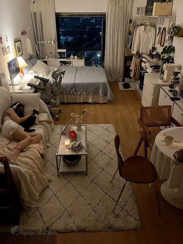 a woman sitting on a couch in a living room next to a bed and table