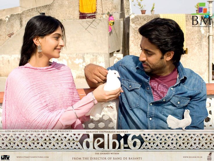 a man and woman standing next to each other in front of a wall with birds on it