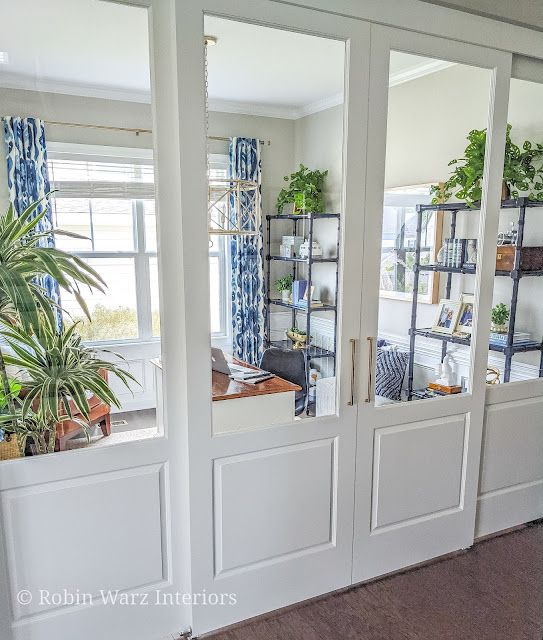 a room with some plants in the window and shelves on the wall next to it