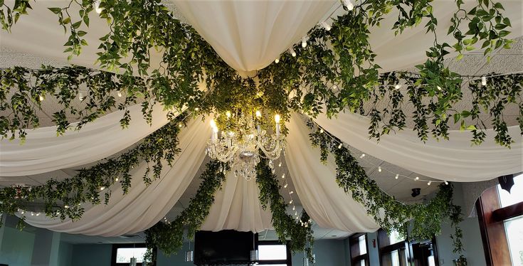 the ceiling is decorated with greenery and chandelier hanging from it's sides