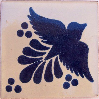 a blue and white tile with a black bird on it's back side in flight