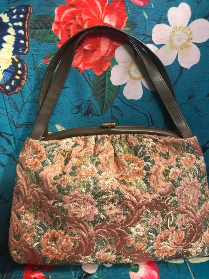 "Vintage 60s brown tapestry purse has beautiful rose pattern in mocha brown, peach, green and ivory. Purse has faux leather handles and trim. Purse is lined with vinyl and has a clear plastic attached coin purse which would also be perfect for ID card. Brass tone metal clasp shows wear otherwise purse is in excellent condition. No Label Purse measures 13\" side to side, @ 9\" tall and 4\" across bottom. Strap is 17\" across." Vintage Beige Tapestry Bag, Vintage Tapestry Bag For Everyday, Vintage Tapestry Bag With Detachable Handle, Vintage Tapestry Satchel With Top Handle, Vintage Tapestry Satchel With Top Carry Handle, Vintage Satchel Shoulder Bag With Rolled Handles, Vintage Brown Tapestry Satchel, Retro Rectangular Tapestry Bags, Vintage Tapestry Tote Bag