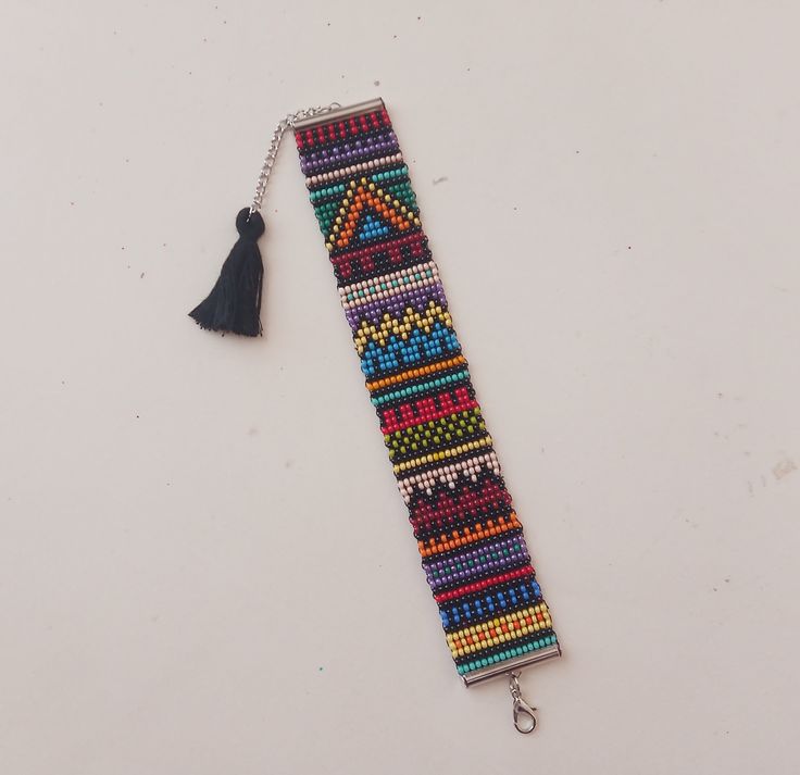 a beaded key chain with a tassel hanging from it's end on a white surface