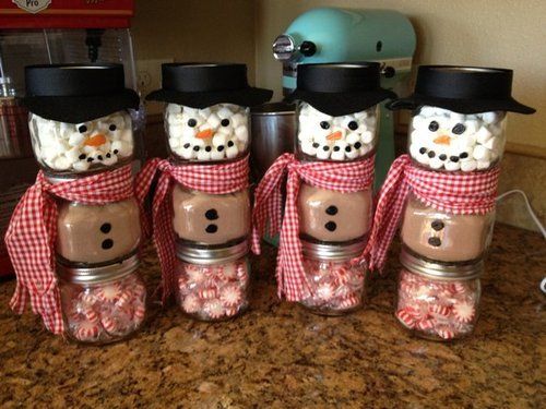 four mason jars with marshmallows and snowmen in them on a counter