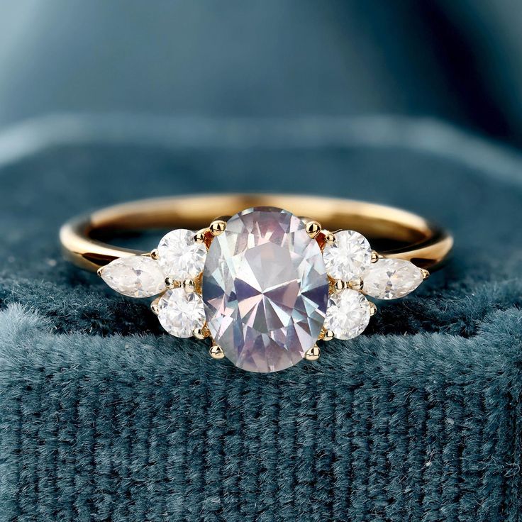 an engagement ring with three stones on it and a blue blanket in the back ground