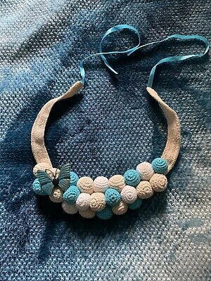 a blue and white beaded necklace on top of a denim material sheet with a cord