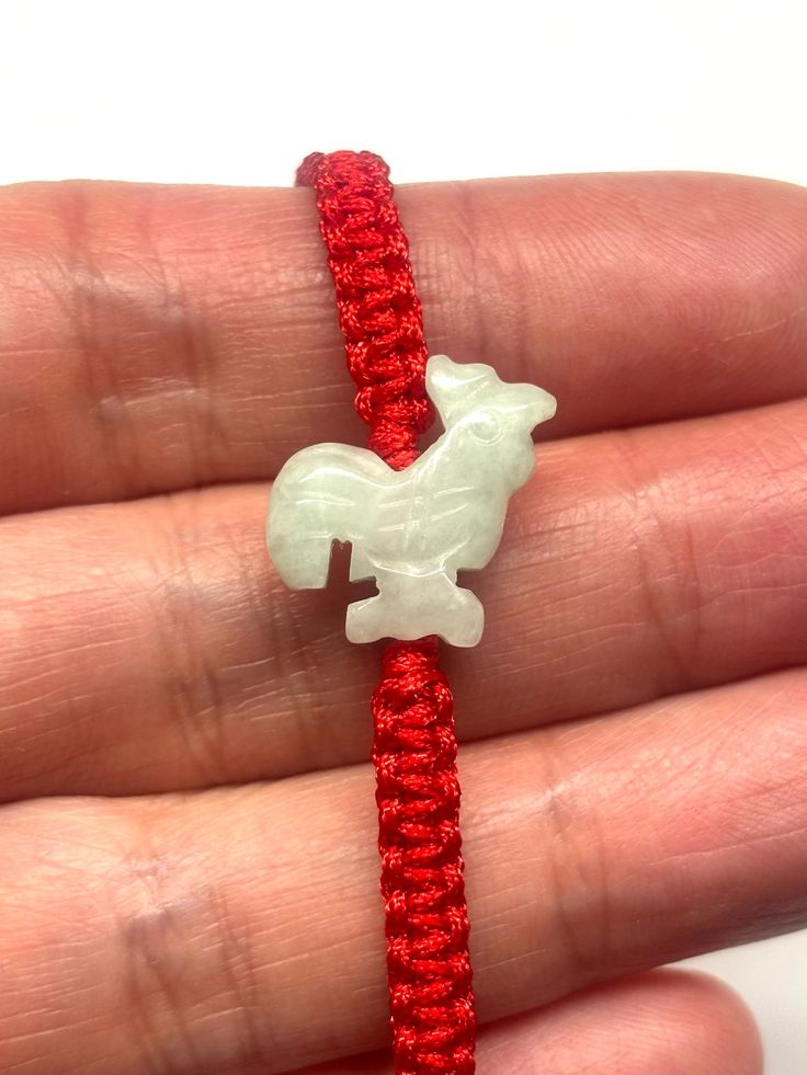 Unique Chinese ethnic style carved jade rooster bracelet. Very beautiful and charming! Perfect gift for your loved ones! In ancient China, Rooster was a lucky charm, representing civil and military official promotion. One rooster denoted one level of promotion. Rooster has red crown on it's head and it signifies utmost fortune (鴻運當頭).  Wearing this jade rooster bracelet is blessing for happiness, luck and promotion!  - Made with carved jade rooster, jade beads and adjustable red cord - approximately 14 mm / 0.55 inches width (widest part), 17 mm / 0.67 inches length (longest part) and 5 mm / 0.2 inches thickness (thickest part) of jade rooster - red cord bracelet drop length - approximately 110 mm / 4.33 inches from one end to the other end and it is adjustable to 55 mm / 2.17 inches short Handmade Red Jade Bracelets, Red Jade Bracelet As Gift, Red Jade Bracelet Gift, Adjustable Red Jade Bracelet, Good Luck Bracelet, Red Crown, Carved Jade, Lucky Bracelet, Jade Bracelet