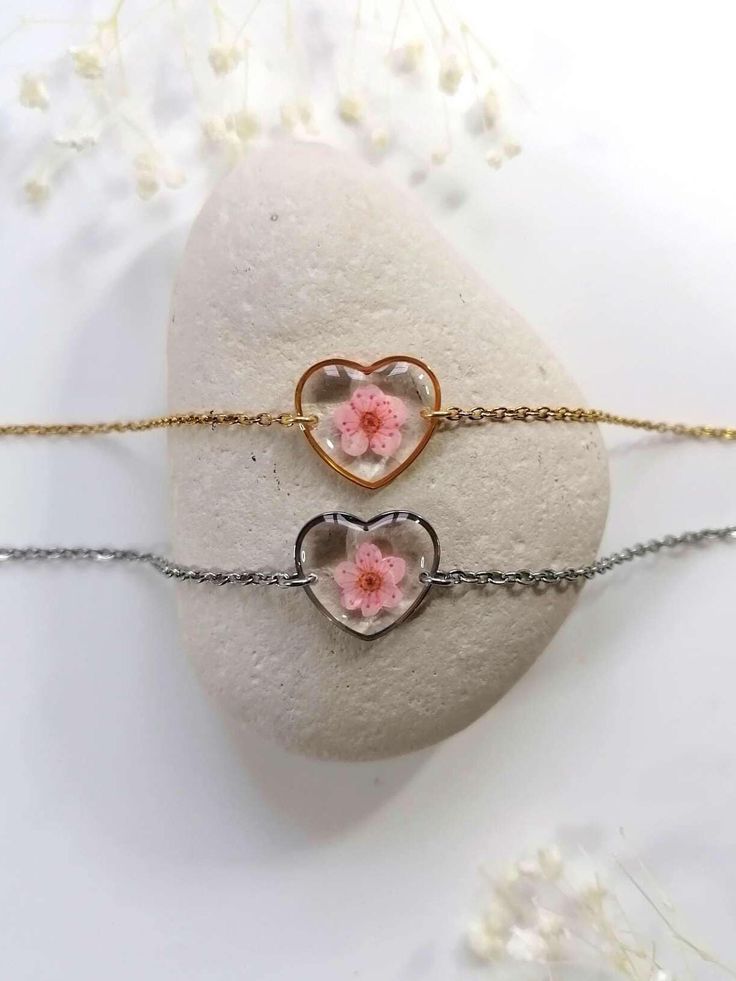 ANAÏS Collection Heart bracelet with a natural pink spirea flower. Diameter of the heart medallion: 15mm Women's or children's bracelet. Women's bracelet: length of 15cm adjustable with 4cm extension (19cm in total) Children's bracelet (5-12 years): length of 12cm adjustable with 4cm extension (16cm in total) 2 Finishes available: - Gold stainless steel - Silver stainless steel Stainless steel is a solid, resistant and hypoallergenic material. Handmade jewelry, in France, with natural pressed flowers, resin and quality materials. Each flower being unique, there may be slight differences in shape or color from one piece of jewelry to another. Shipped in its "Florelia Bijoux" box. Maintenance advice: rub the resin medallion with a small cloth (provided with the jewelry), without water or pro