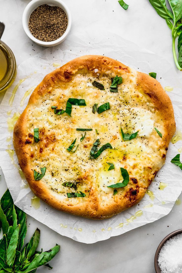 a pizza sitting on top of a piece of paper next to some spices and herbs