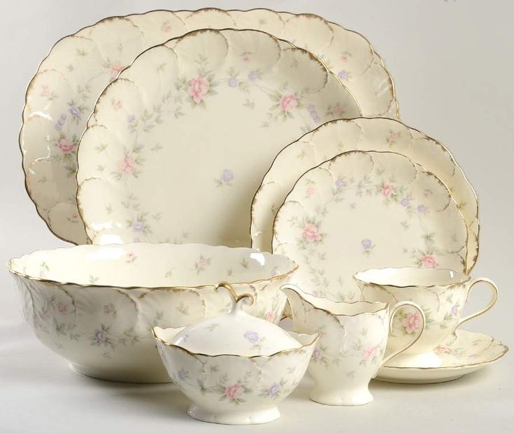 a set of porcelain dishes and cups with floral designs on the rims are shown