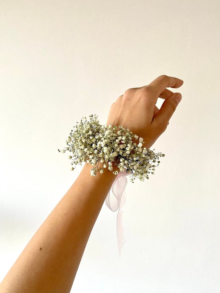 a woman's hand holding a bouquet of baby's breath on her wrist