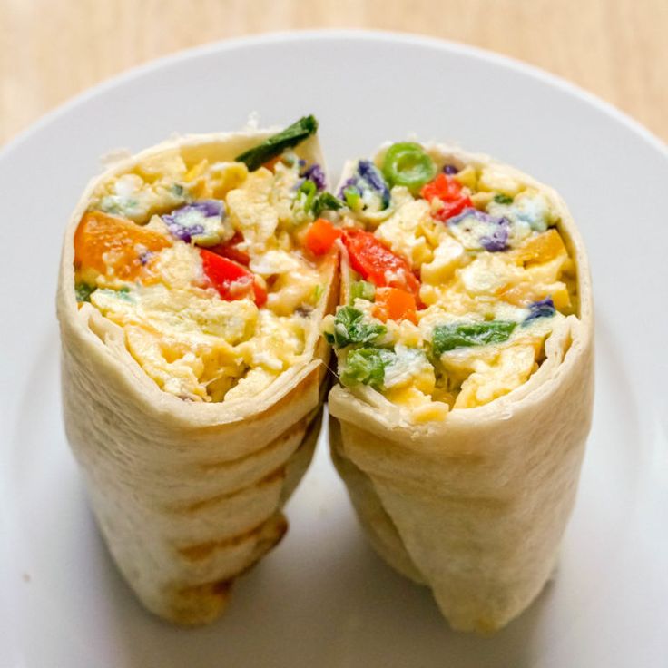 two burritos on a plate with one cut in half to show the filling