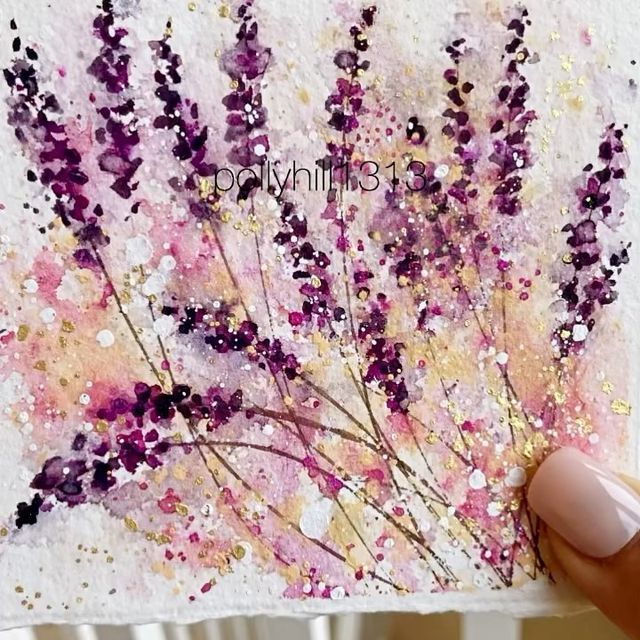 a hand holding up a piece of paper with flowers painted on it and glitters