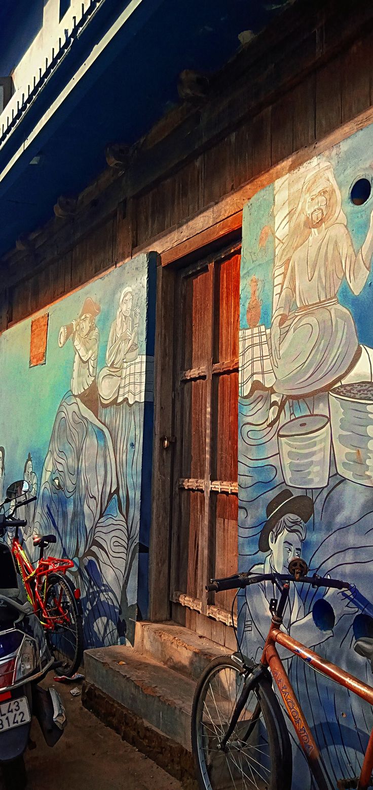 two bikes parked next to each other in front of a building with paintings on it