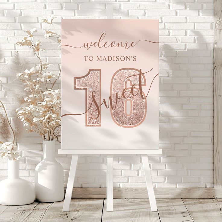 a welcome sign sitting on top of a wooden easel next to vases and flowers