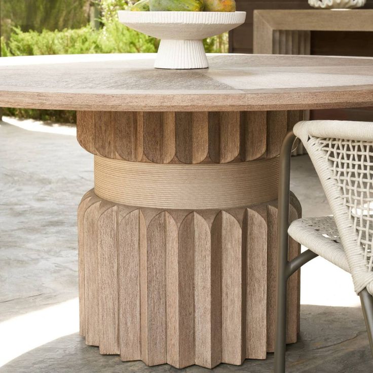 an outdoor table with chairs and a vase on it's pedestal, in the middle of a patio