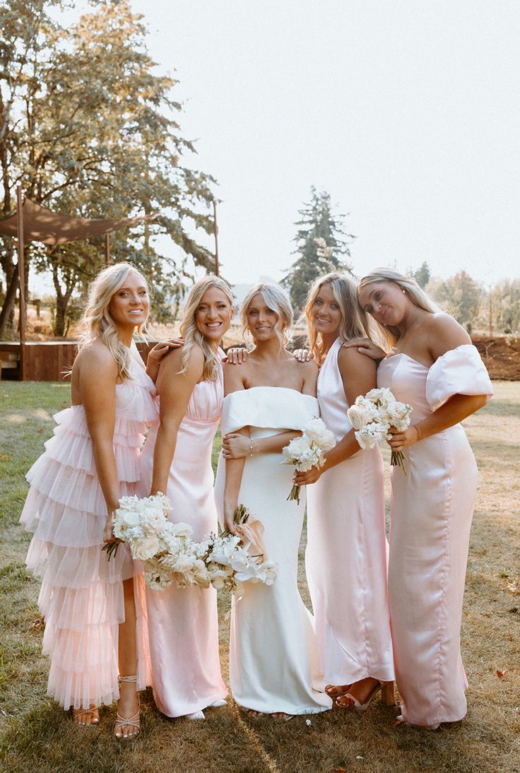 a group of women standing next to each other on top of a grass covered field