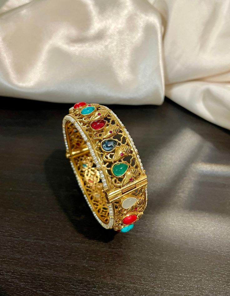 Traditional Temple Navrathan / Navratan / Multicolor Semi Precious stone studded openable Ganesh Motif Bracelet Bangle in Matte gold finish. A perfect piece of art always a keeper in your jewelry trinket that goes with Ethnic Attire /  Indian outfits.  👉🏻Size Available:  2.5 Openable  ✅Check other styles available in our store https://www.etsy.com/shop/KKsCulture Send us an email if you need help!  SHIPPING & TURNAROUND  👉🏻Please check listings for shipping and turnaround times.  👉🏻We foll Multicolor Bracelet With Intricate Design As A Gift, Multicolor Bracelets With Intricate Design For Gift, Multicolor Bracelets With Intricate Design As Gift, Stone Work Bracelets For Puja And Festivals, Traditional Bracelets With Stone Work For Gifts, Traditional Stone Work Bracelet For Gift, Festive Stone Work Bracelets For Puja, Multicolor Bracelet Jewelry For Puja, Traditional Stone Work Bracelets For Festive Occasions