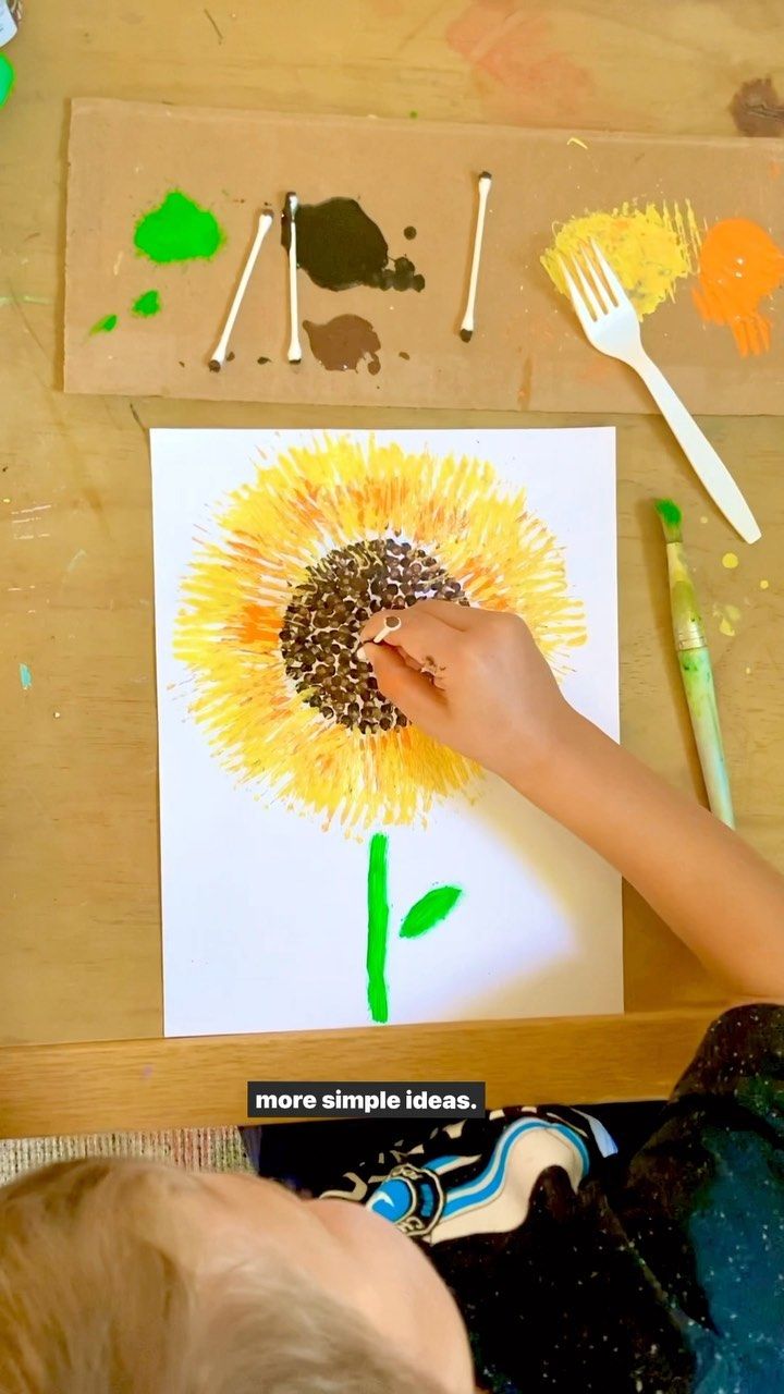 a child is painting a sunflower with acrylic paint on paper and watercolors