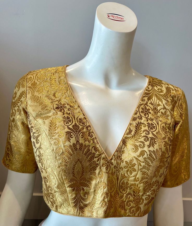 A golden color blouse Product details Fabric - silk blend Bust size 40" Waist 32" sleeve length 10" Can be tailored to fit 42" For extra charges Elegant Formal Choli With Zari Work, Elegant Choli With Zari Work For Formal Occasions, Elegant V-neck Blouse For Festive Occasions, Elegant V-neck Traditional Wear With Pallu, Elegant Festive V-neck Blouse, Traditional Gold V-neck Tops, Formal Festive Raw Silk Choli, Festive Formal Raw Silk Choli, Formal Festive Silk Choli