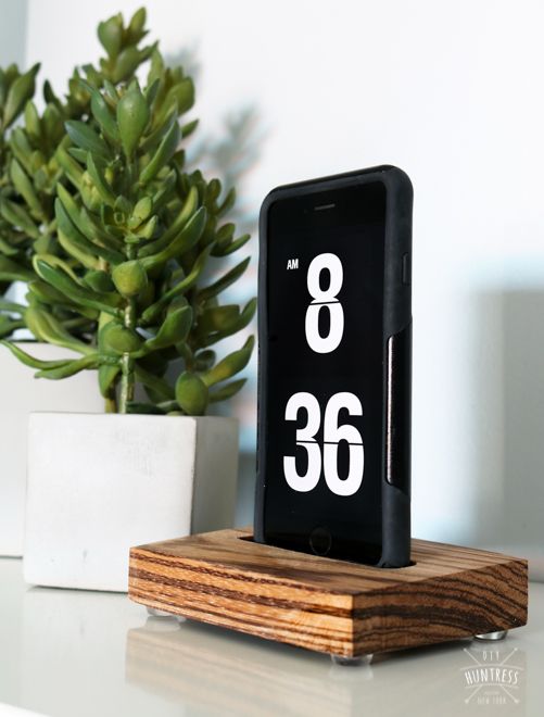 a cell phone sitting on top of a wooden stand next to a potted plant