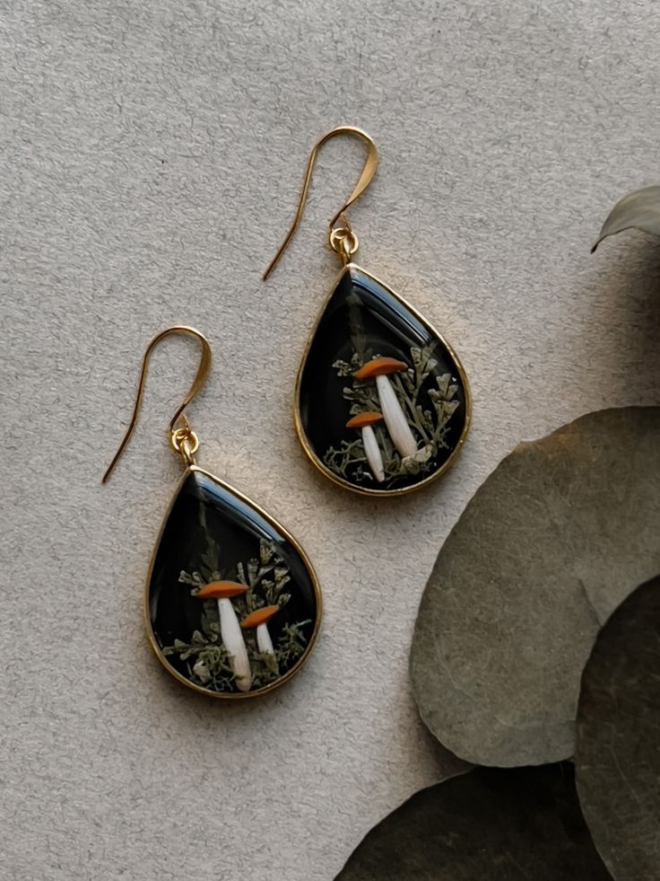 a pair of earrings sitting on top of a table next to a potted plant