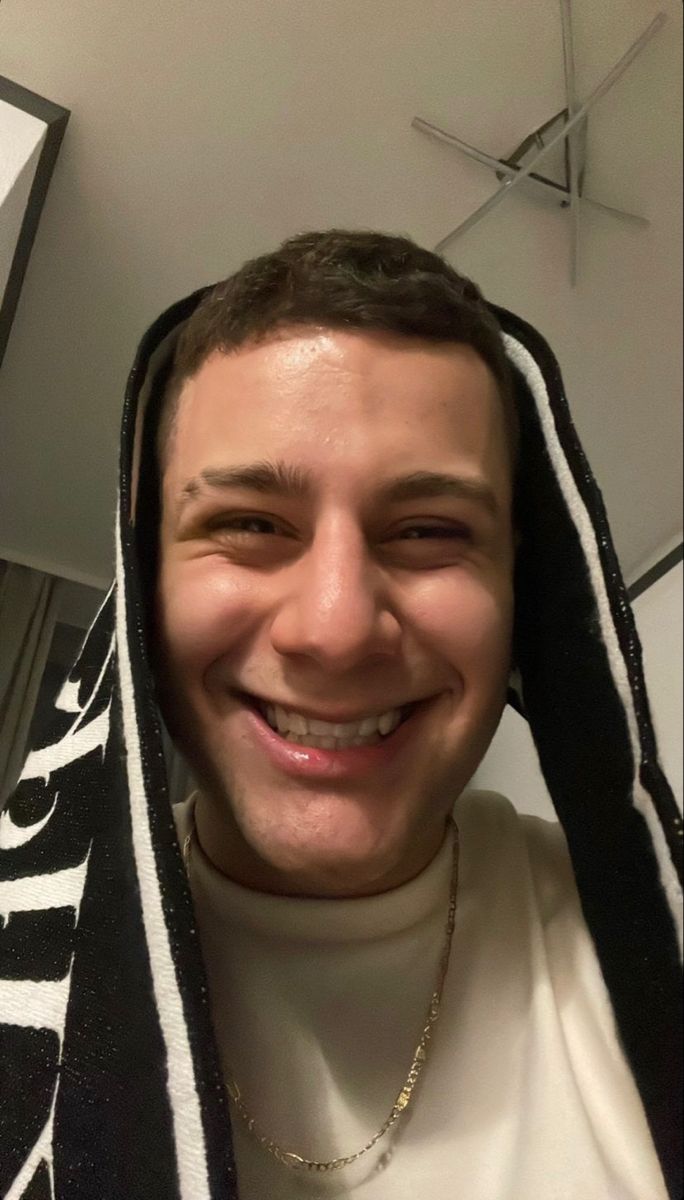 a man wearing a black and white striped towel over his head smiling at the camera