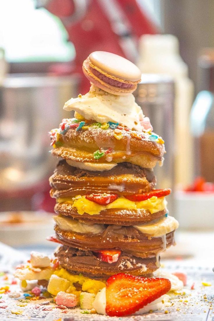 a stack of pancakes sitting on top of a table covered in frosting and sprinkles