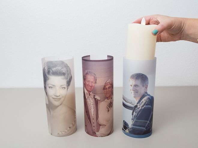 a hand holding a candle with three photos on it next to a cup that has a lighter in it