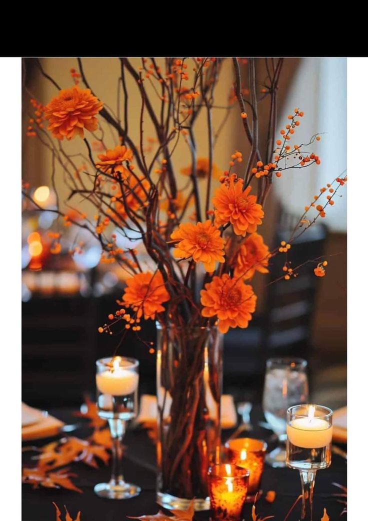 a vase filled with flowers and candles on top of a black tablecloth covered table