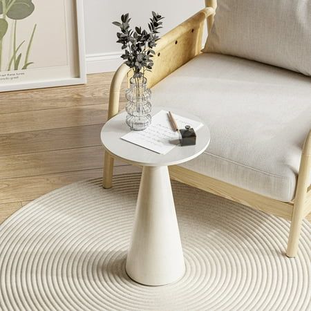 a white table sitting on top of a wooden floor next to a chair and potted plant