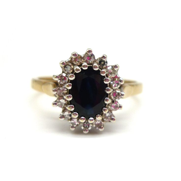 a gold ring with an oval blue stone surrounded by small pink and white diamonds on it