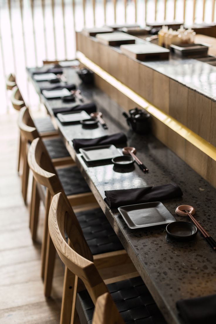 a long table with black plates and chopsticks on it