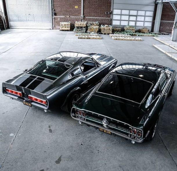 two black muscle cars parked next to each other