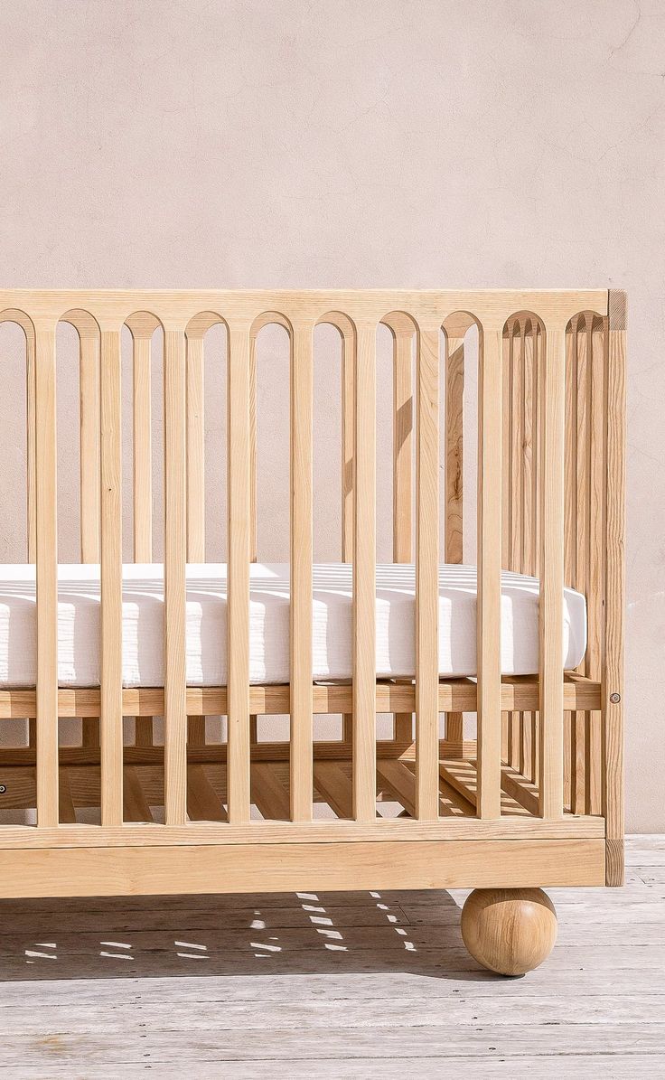 a wooden crib sitting on top of a hard wood floor next to a wall